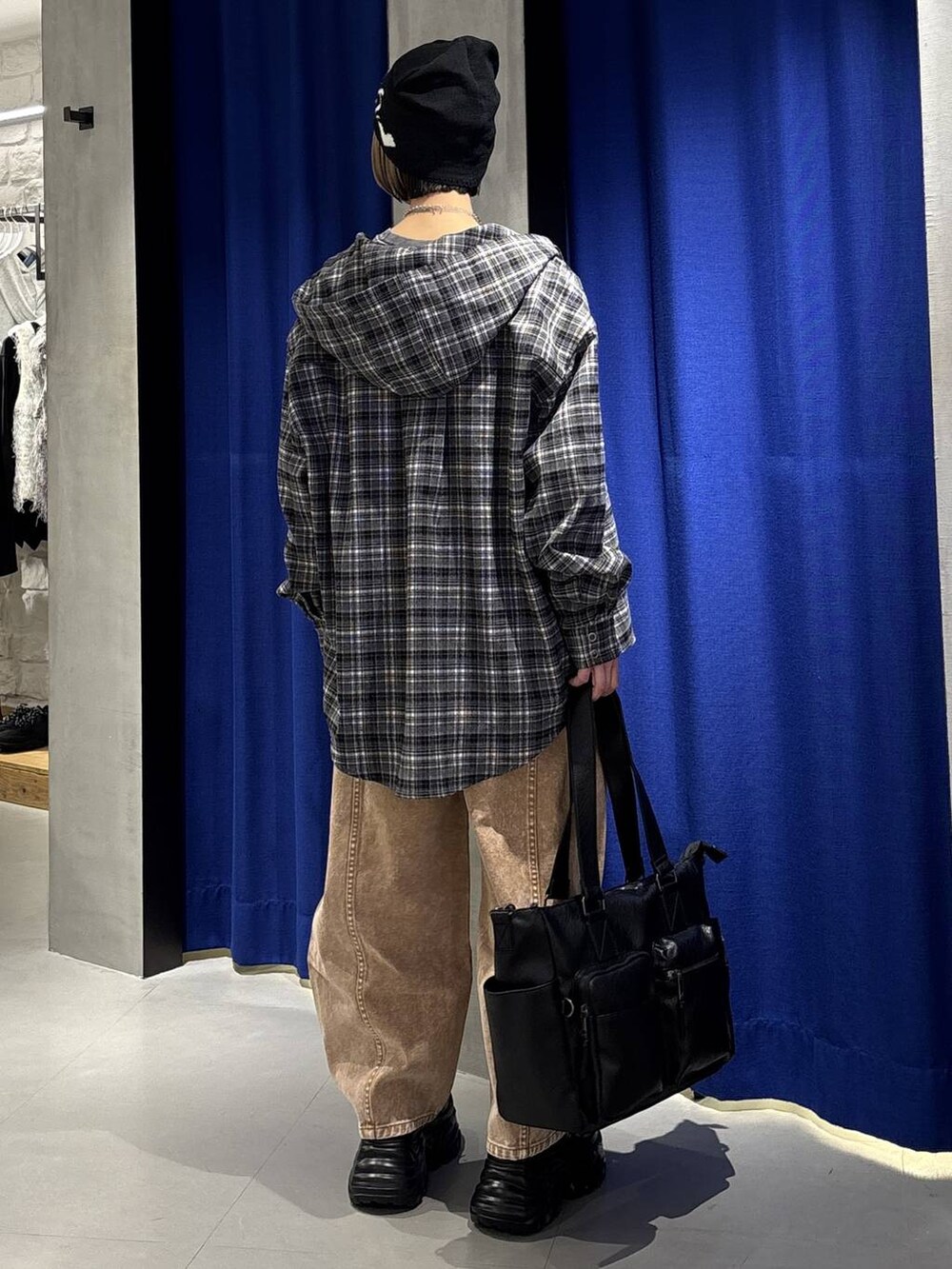 ブラック系のスニーカー、ブラック系のボストンバッグ、ブラウン系のデニムパンツを着用したレディースの冬コーディネートの5枚目の写真