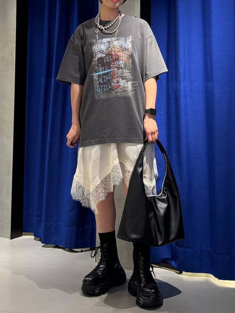 ブラック系のブーツ、ブラック系のトートバッグ、ホワイト系のチュニックを着用したレディースの春コーディネートの4枚目の写真