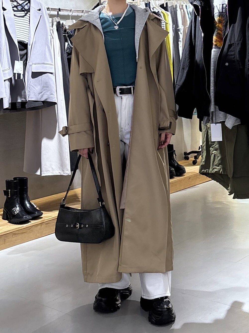 ブラック系のスニーカー、ホワイト系のデニムパンツ、ベージュ系のトレンチコートを着用したレディースの冬コーディネートの2枚目の写真