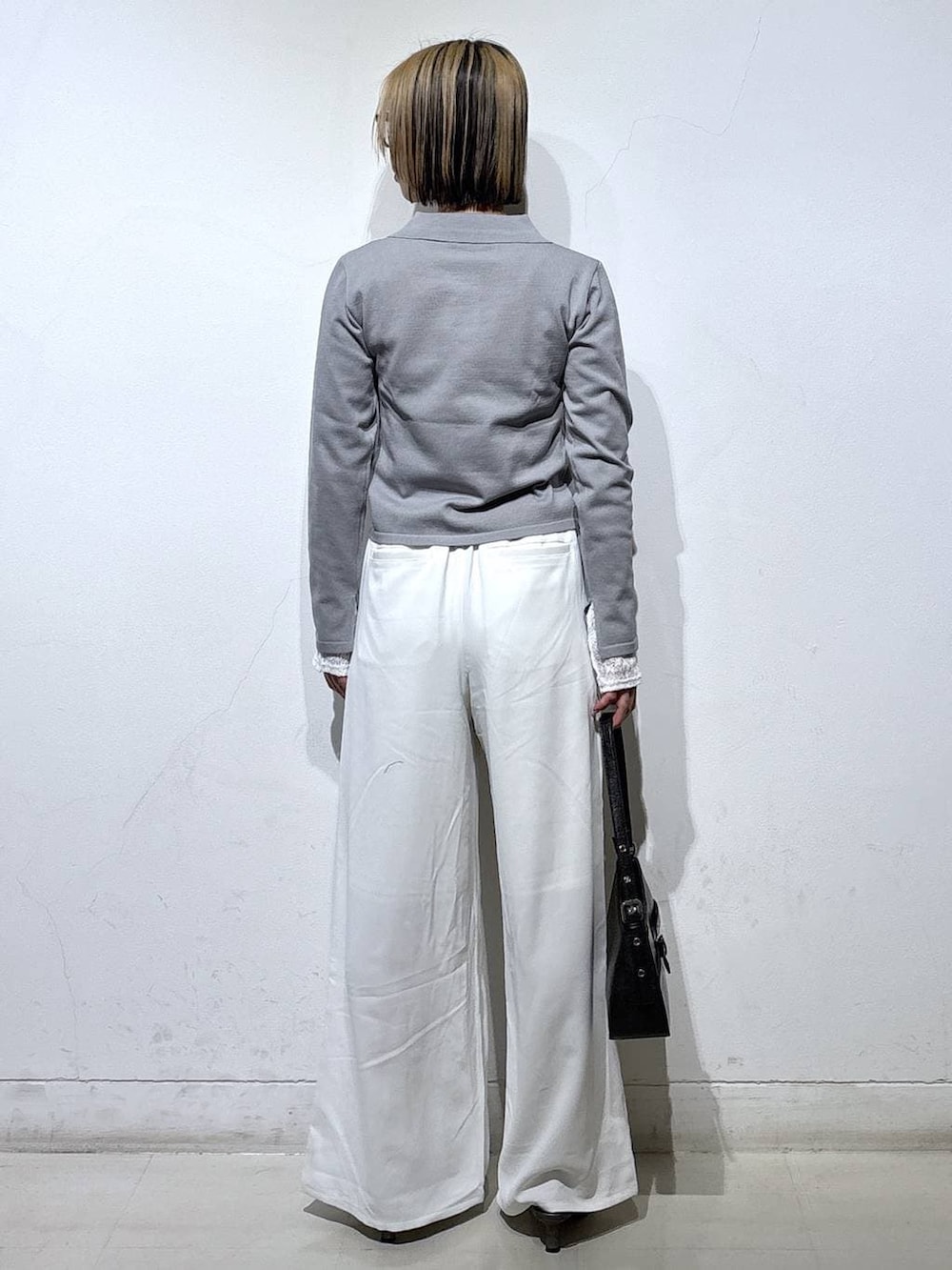 ブラック系のハンドバッグ、ブラウン系のサンダル、ホワイト系のスラックスを着用したレディースの春コーディネートの4枚目の写真