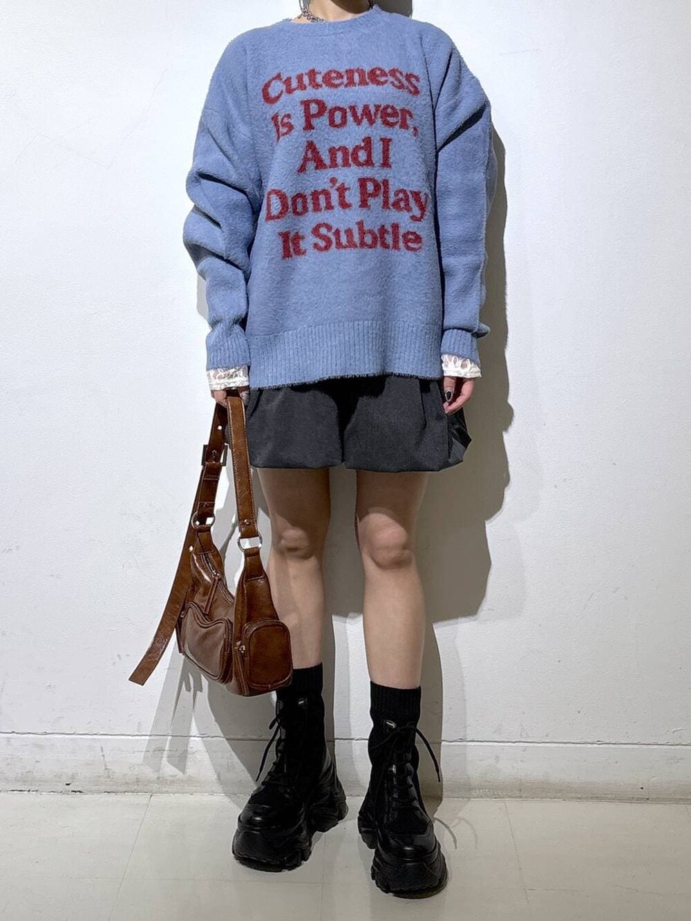 ブラック系のブーツ、ホワイト系のTシャツ/カットソー、ブラウン系のショルダーバッグを着用したレディースの冬コーディネートの2枚目の写真