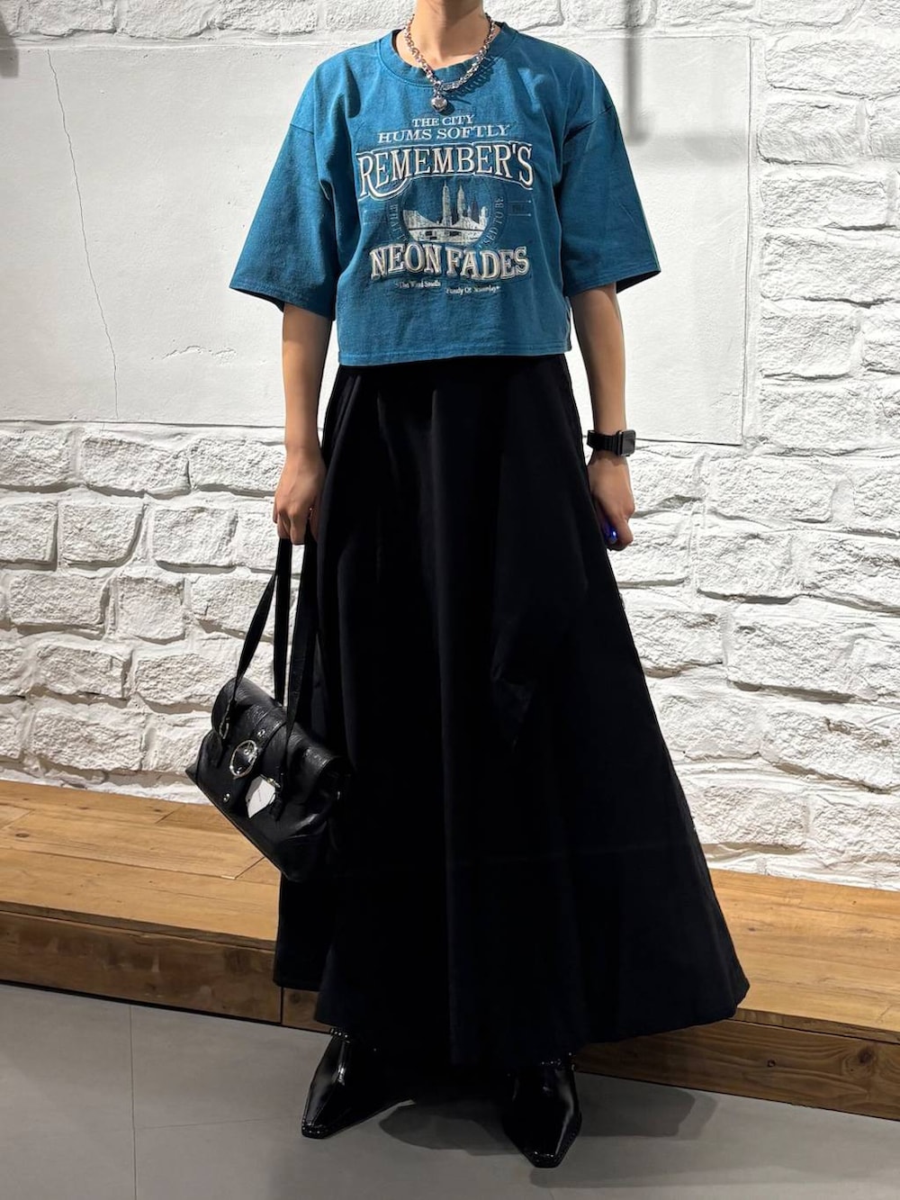 ブラック系のスカート、ブルー系のTシャツ/カットソー、ブラック系のショルダーバッグを着用したレディースの夏コーディネートの3枚目の写真