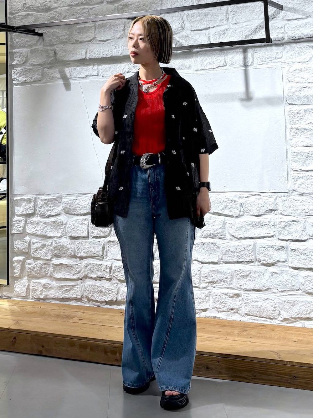 ブルー系のデニムパンツ、ブラウン系のショルダーバッグ、ブラック系のサンダルを着用したレディースの春コーディネートの2枚目の写真