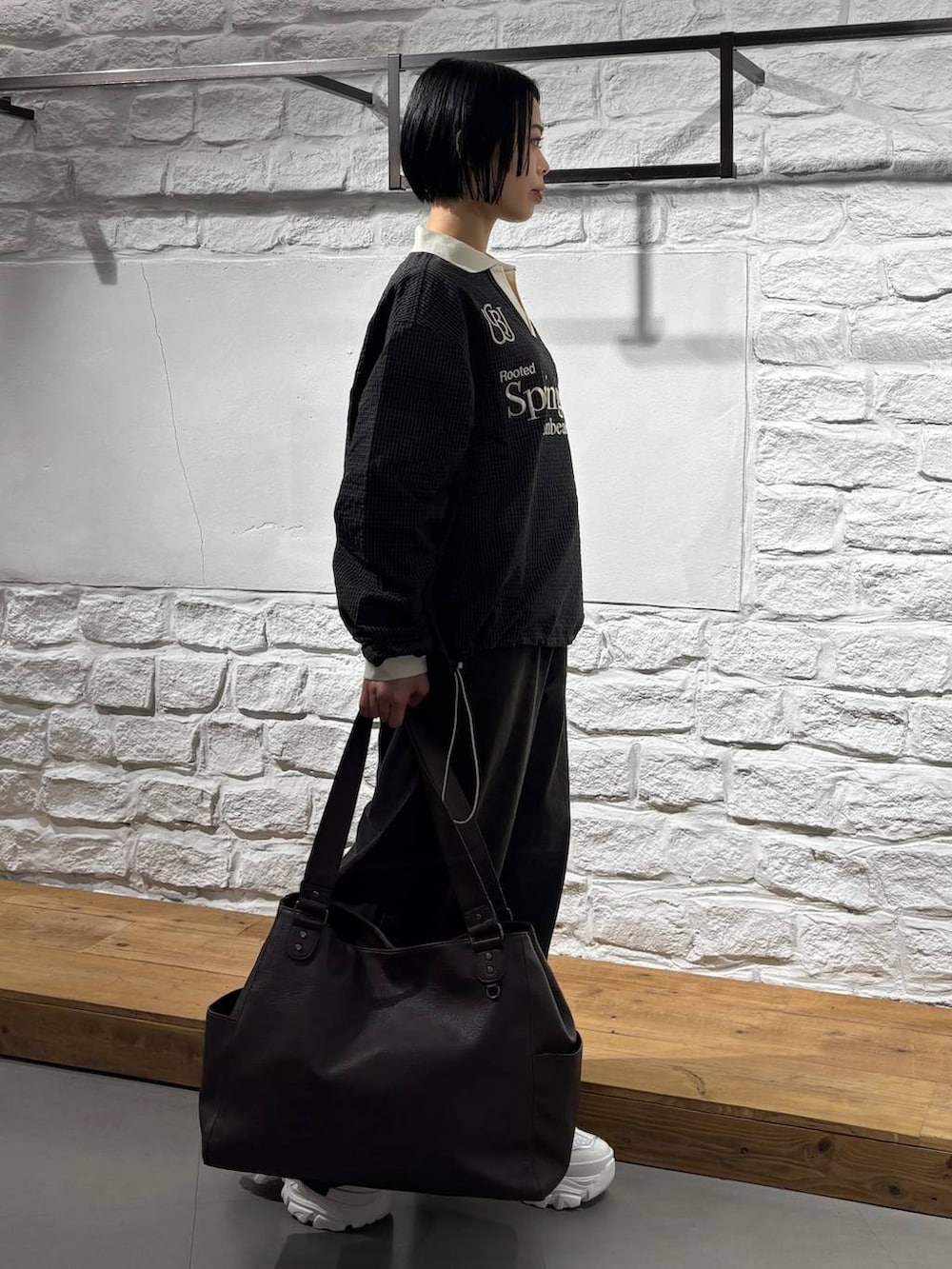 ホワイト系のスニーカー、ブラック系のデニムパンツ、ブラウン系のトートバッグを着用したレディースの秋コーディネートの3枚目の写真