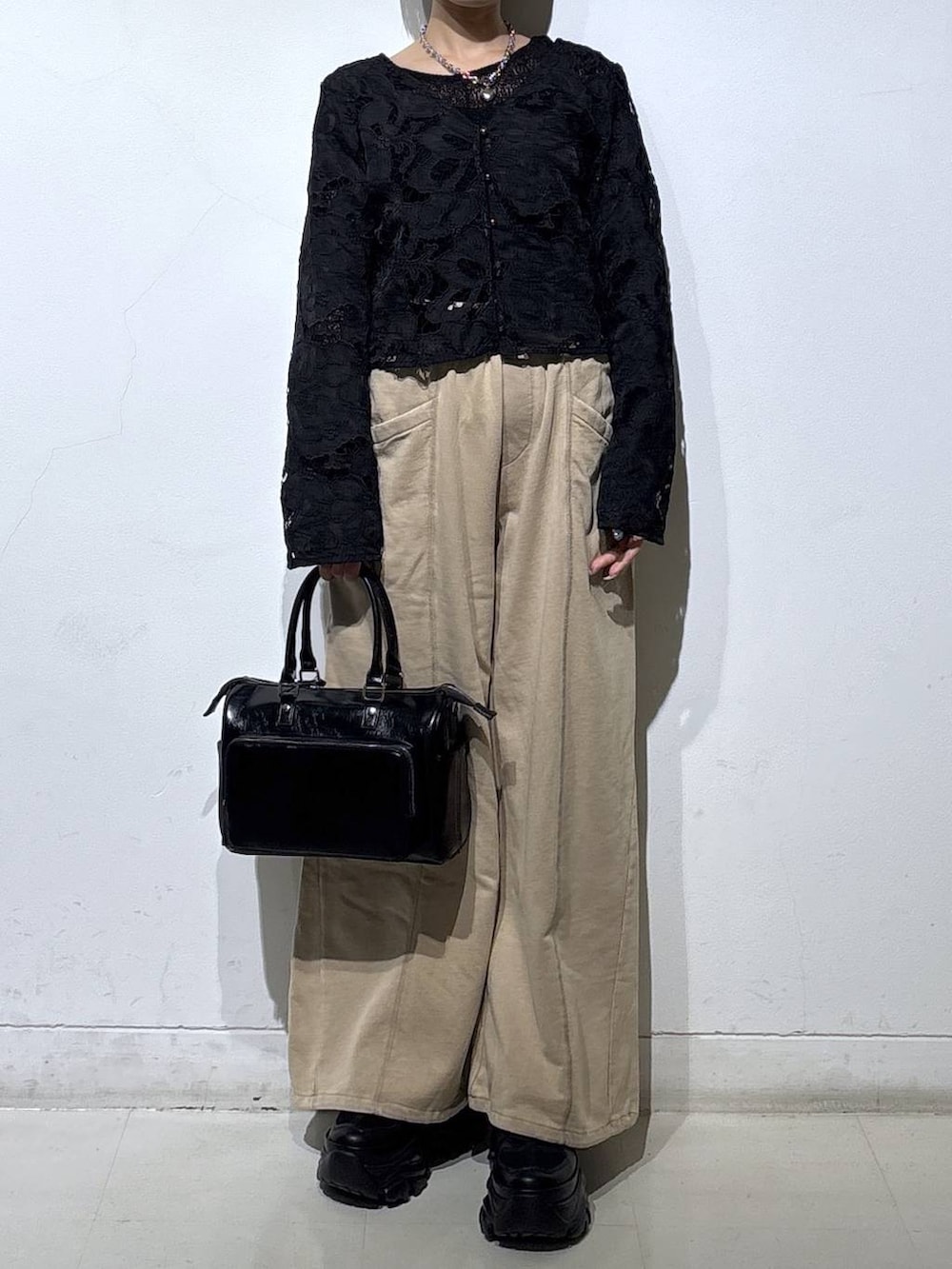 ブラック系のスニーカー、ブラック系のショルダーバッグ、ブラウン系のスウェットパンツを着用したレディースの冬コーディネートの2枚目の写真