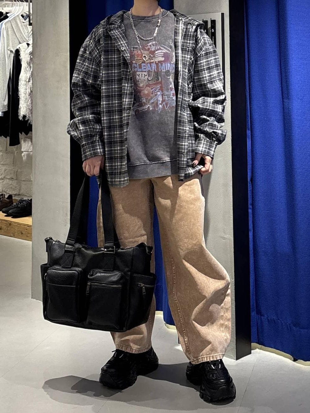 ブラック系のスニーカー、ブラック系のボストンバッグ、ブラウン系のデニムパンツを着用したレディースの冬コーディネートの2枚目の写真