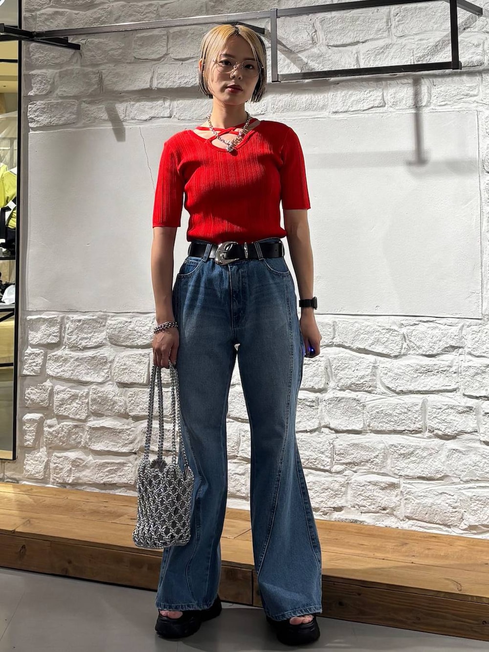 ブルー系のデニムパンツ、ブラック系のサンダル、レッド系のニット/セーターを着用したレディースの春コーディネートの2枚目の写真