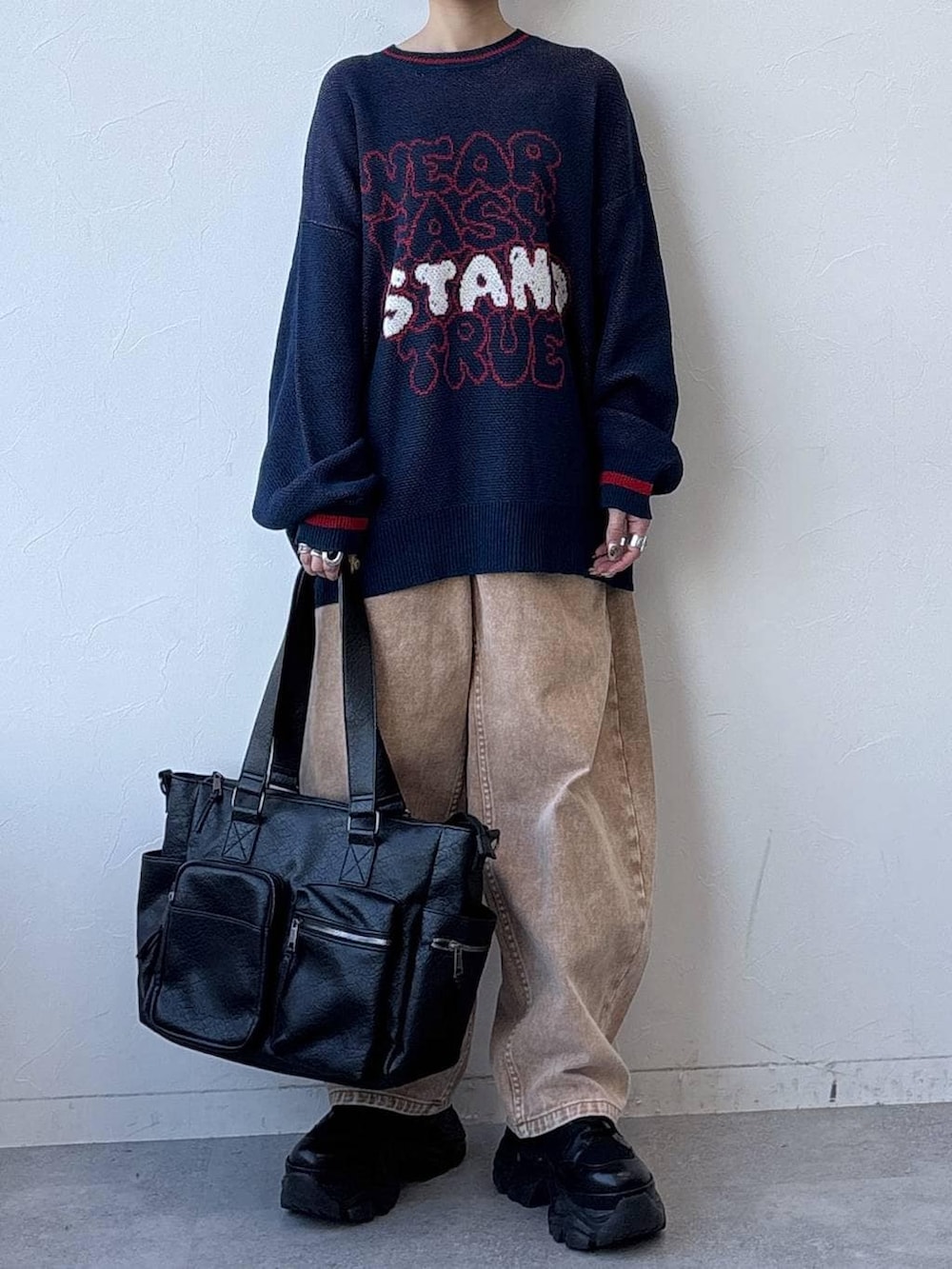 ブラック系のスニーカー、ブラック系のボストンバッグ、ブラウン系のデニムパンツを着用したレディースの冬コーディネートの2枚目の写真