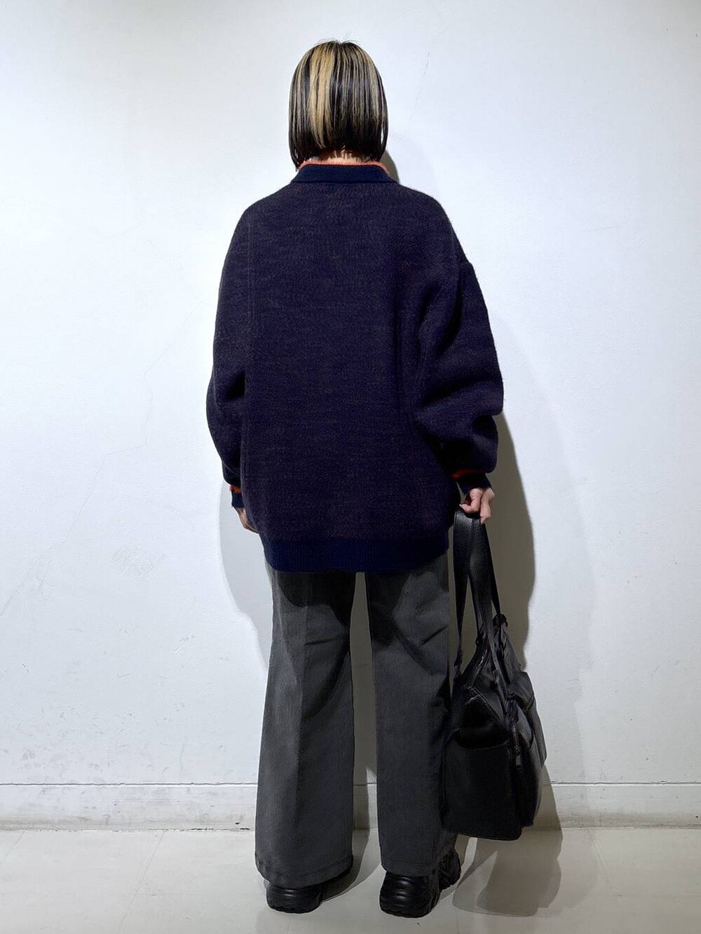 ブラック系のブーツ、ブラック系のボストンバッグ、ブルー系のニット/セーターを着用したレディースの秋コーディネートの4枚目の写真