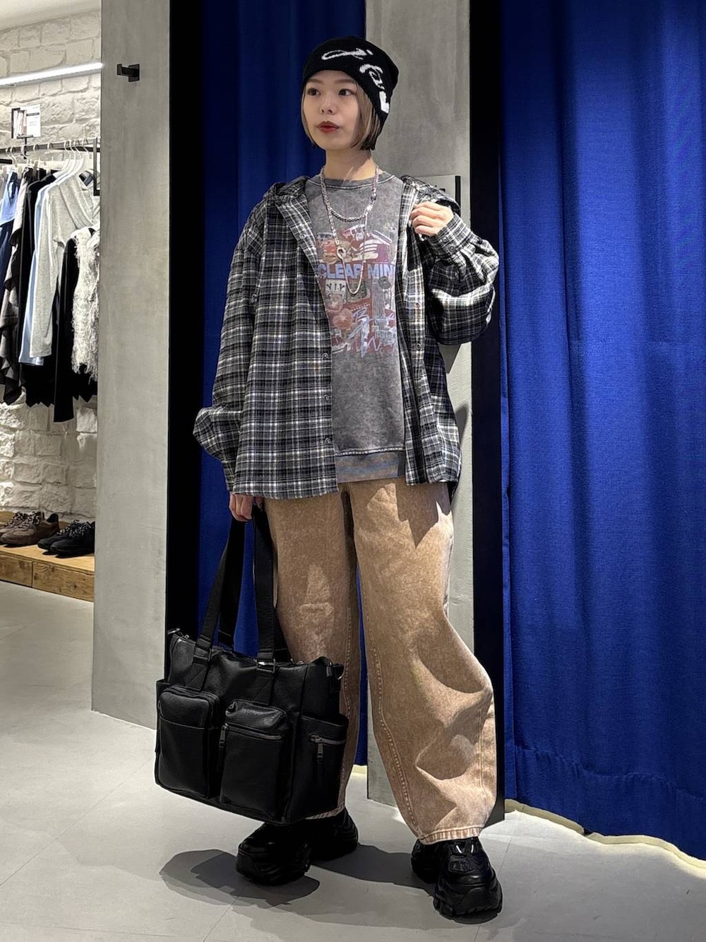 ブラック系のスニーカー、ブラック系のボストンバッグ、ブラウン系のデニムパンツを着用したレディースの冬コーディネートの3枚目の写真