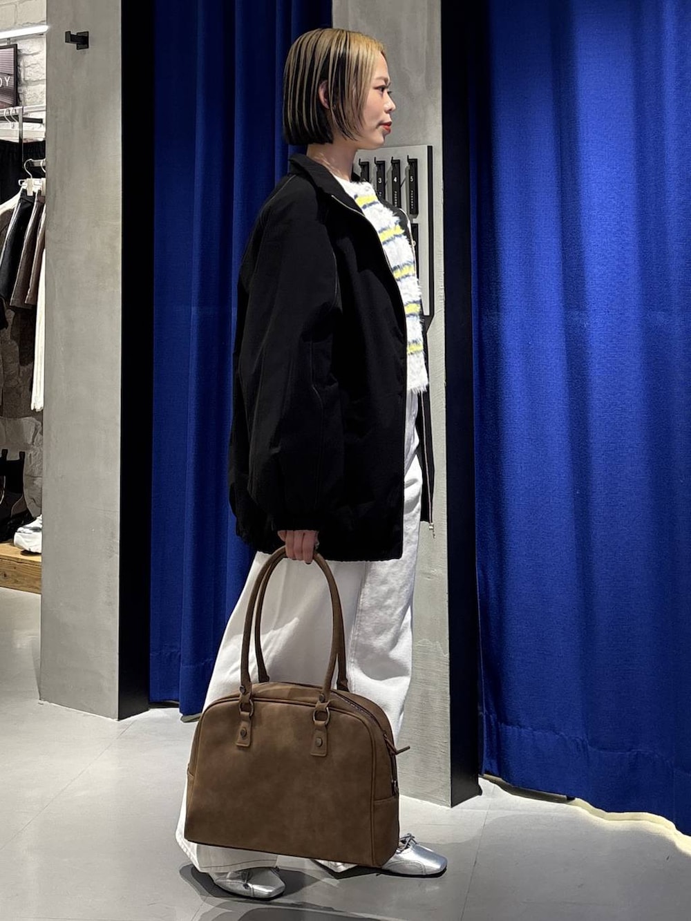 ベージュ系のボストンバッグ、ホワイト系のスラックス、ブラック系のナイロンジャケットを着用したレディースの冬コーディネートの4枚目の写真