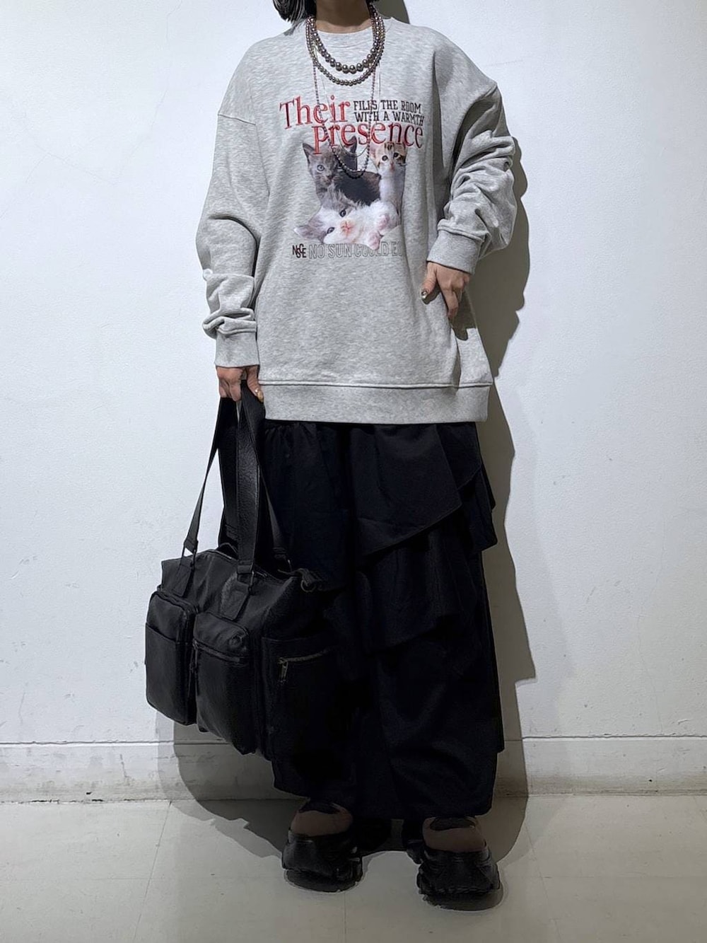 ブラウン系のブーツ、ブラック系のボストンバッグ、ブラック系のスカートを着用したレディースの冬コーディネートの2枚目の写真