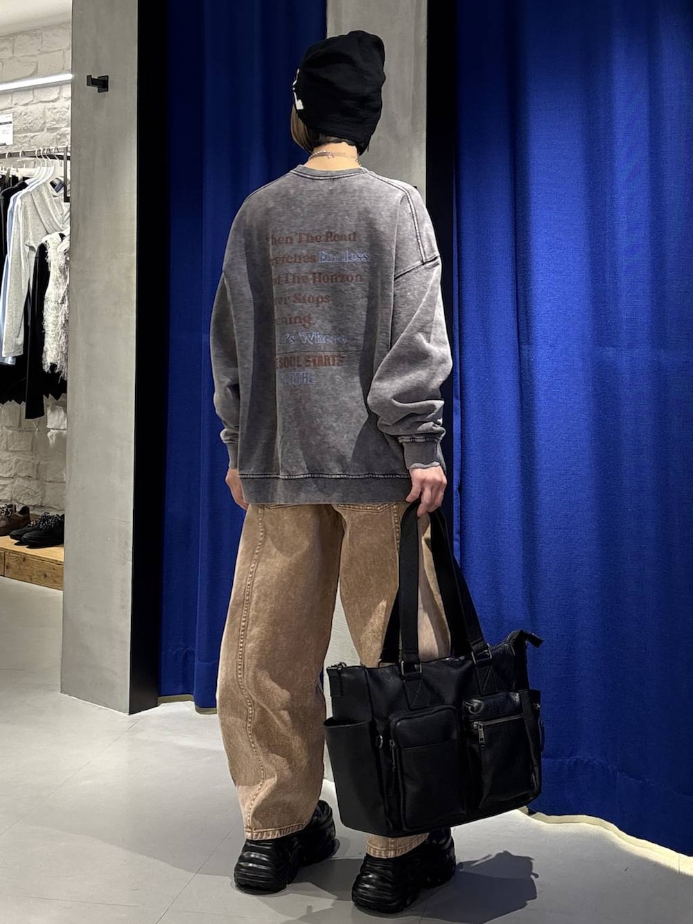 ブラック系のスニーカー、ブラック系のボストンバッグ、ブラウン系のデニムパンツを着用したレディースの冬コーディネートの5枚目の写真