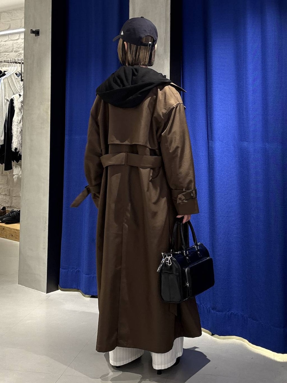 グレー系のニット/セーター、ブラウン系のトレンチコート、ブラック系のショルダーバッグを着用したレディースの冬コーディネートの5枚目の写真