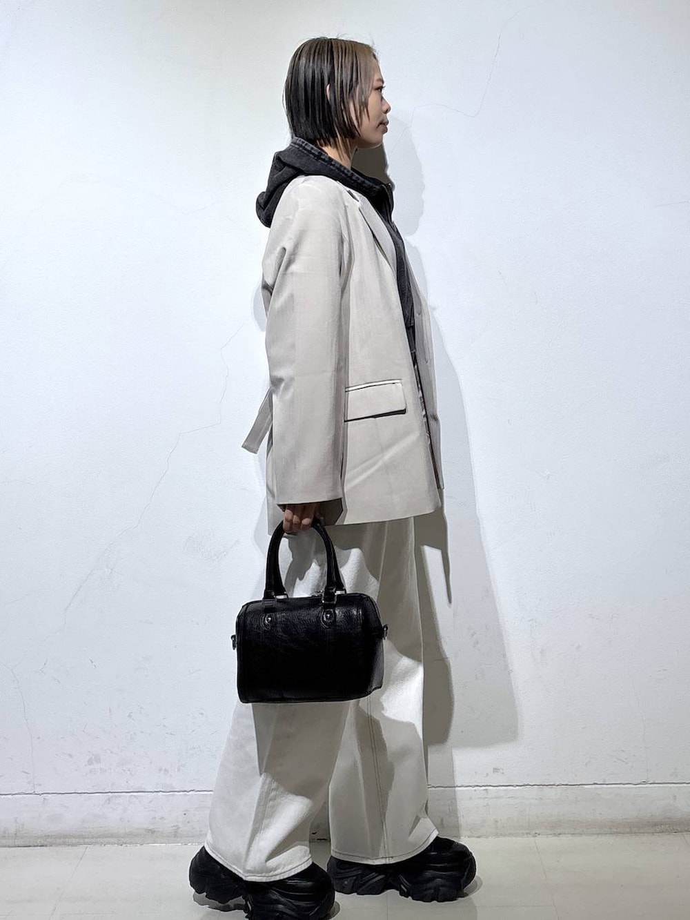 ブラック系のブーツ、ブラック系のTシャツ/カットソー、ホワイト系のスラックスを着用したレディースの冬コーディネートの4枚目の写真