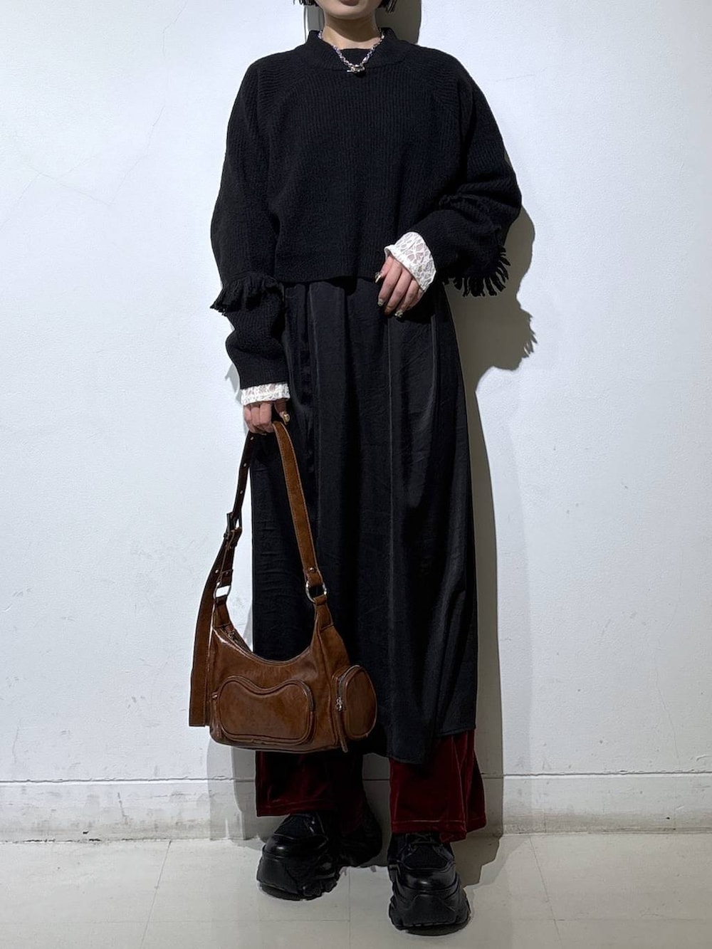 ブラック系のスニーカー、ホワイト系のTシャツ/カットソー、ブラウン系のショルダーバッグを着用したレディースの冬コーディネートの2枚目の写真