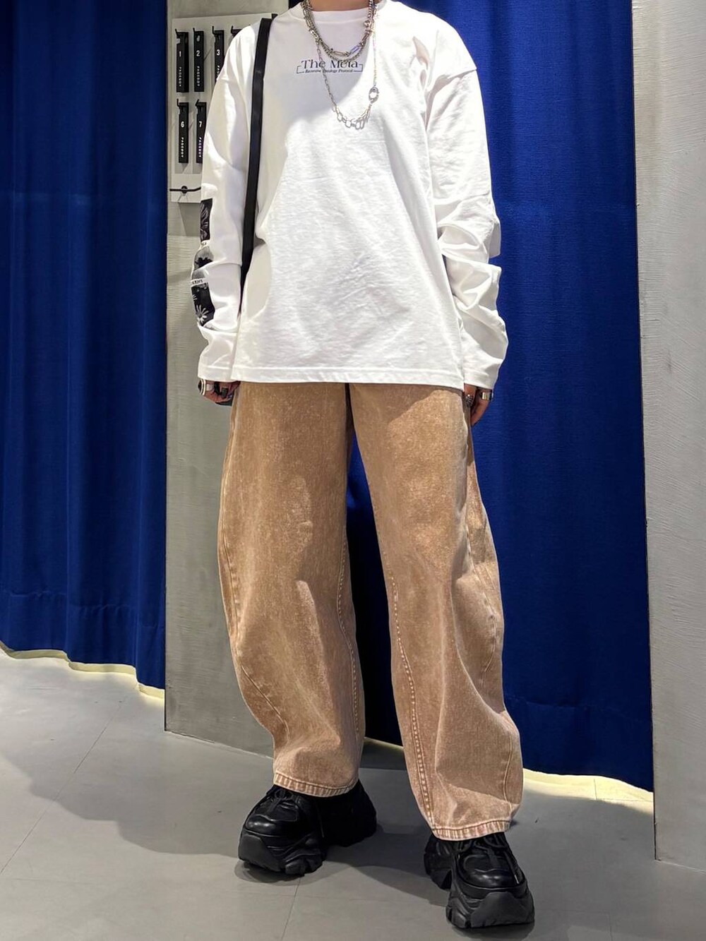ブラック系のスニーカー、ブラウン系のデニムパンツ、ブラック系のショルダーバッグを着用したレディースの春コーディネートの3枚目の写真