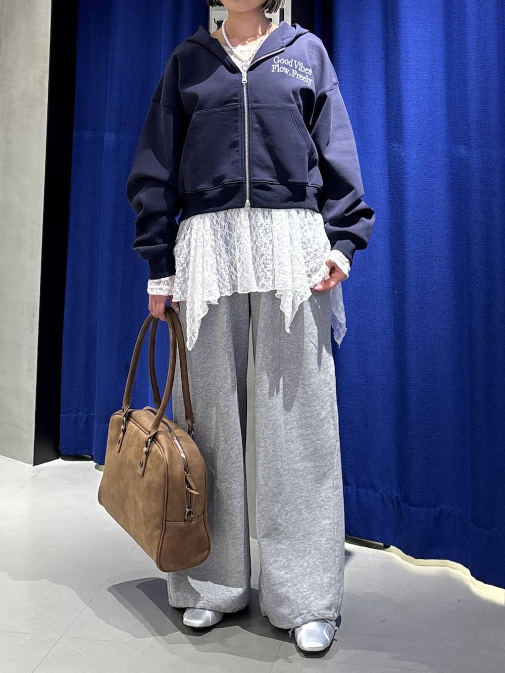 イエロー系のボストンバッグ、ブルー系のパーカー、グレー系のスウェットパンツを着用したレディースの冬コーディネートの2枚目の写真