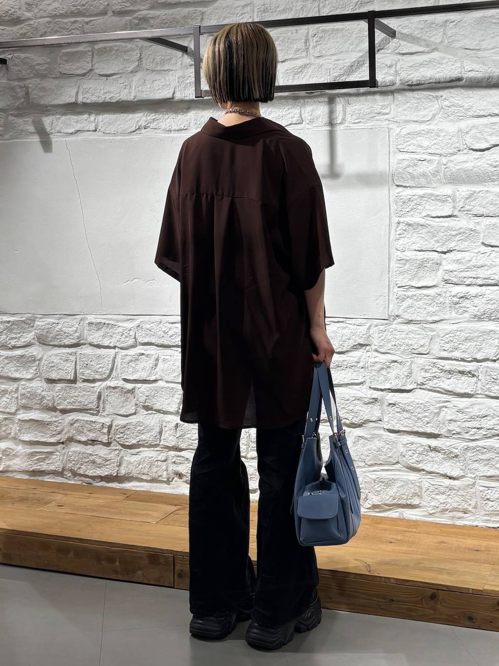 ブラック系のスニーカー、ブラック系のデニムパンツ、ブルー系のハンドバッグを着用したレディースの春コーディネートの5枚目の写真