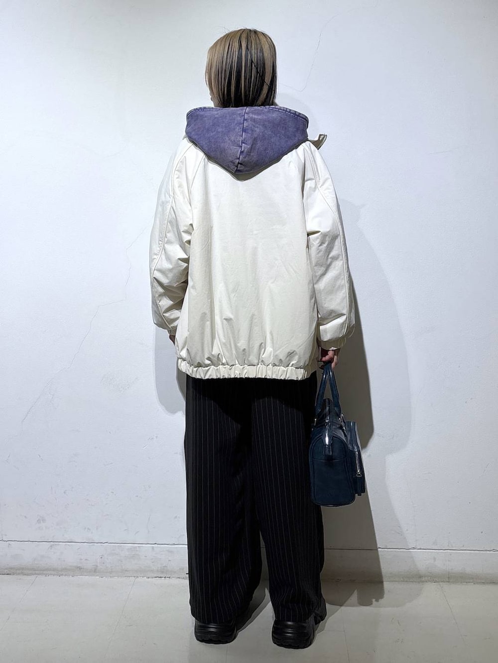 ブラック系のブーツ、ホワイト系のナイロンジャケット、ブルー系のパーカーを着用したレディースの冬コーディネートの4枚目の写真