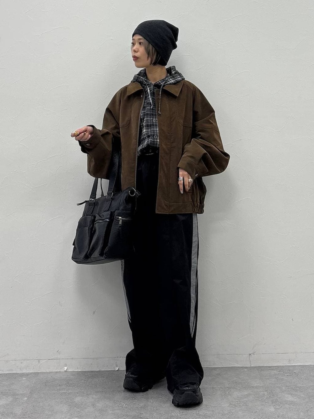 ブラック系のスニーカー、グリーン系のボストンバッグ、ブラウン系のブルゾンを着用したレディースの冬コーディネートの2枚目の写真