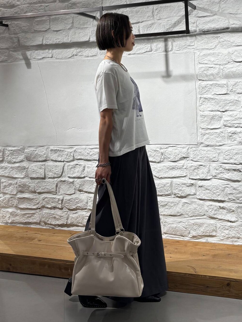 グレー系のスラックス、ホワイト系のTシャツ/カットソー、ホワイト系のショルダーバッグを着用したレディースの夏コーディネートの5枚目の写真