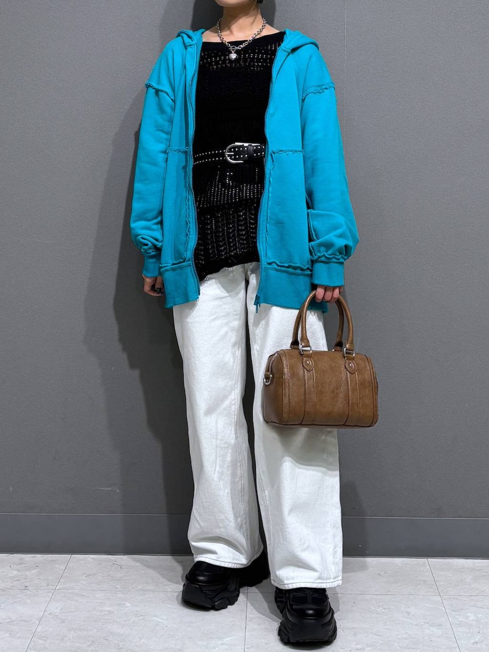 ブラック系のスニーカー、ホワイト系のスラックス、ブラウン系のボストンバッグを着用したレディースの春コーディネートの3枚目の写真