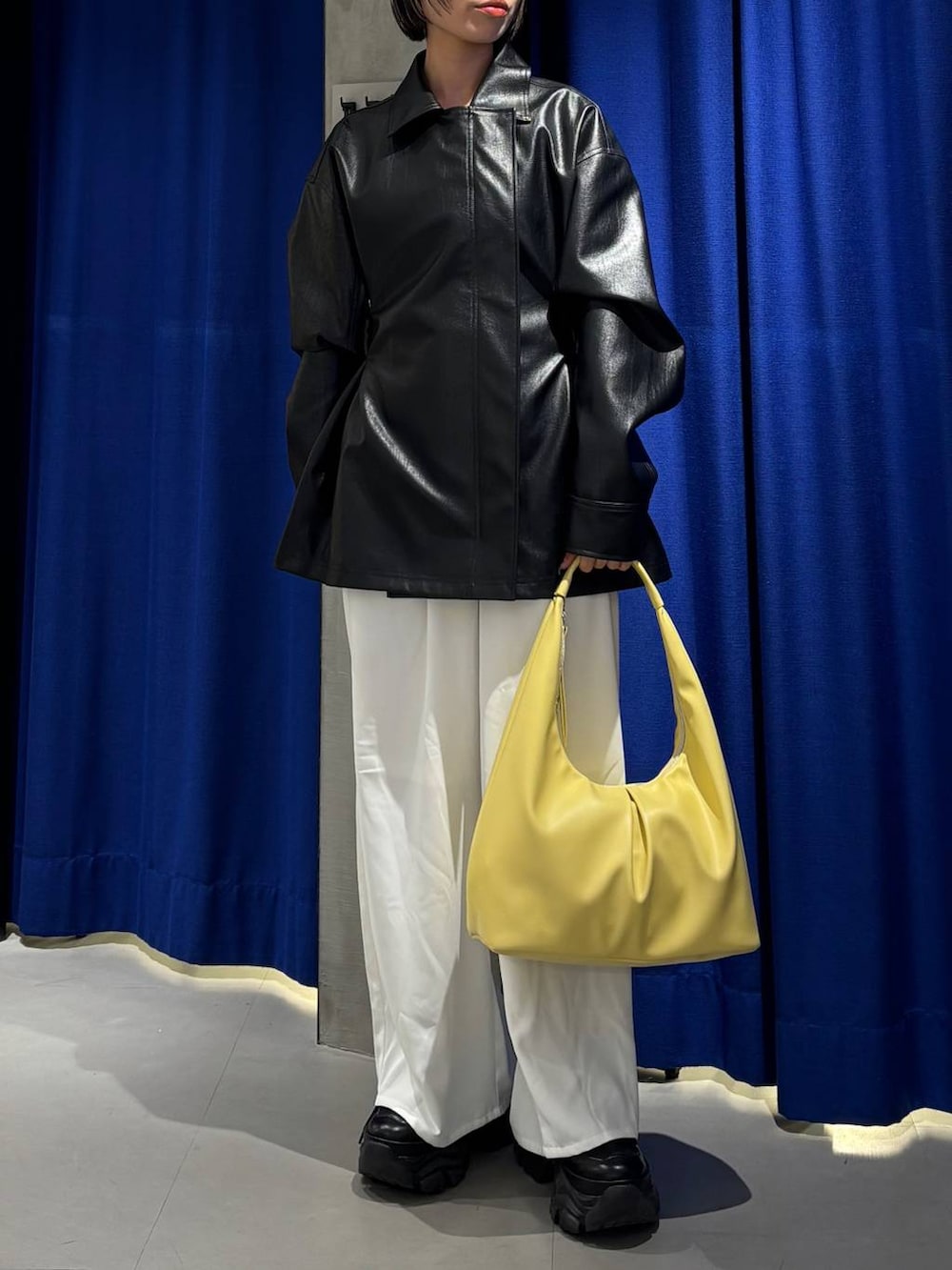 ブラック系のスニーカー、イエロー系のトートバッグ、ホワイト系のスラックスを着用したレディースの春コーディネートの2枚目の写真