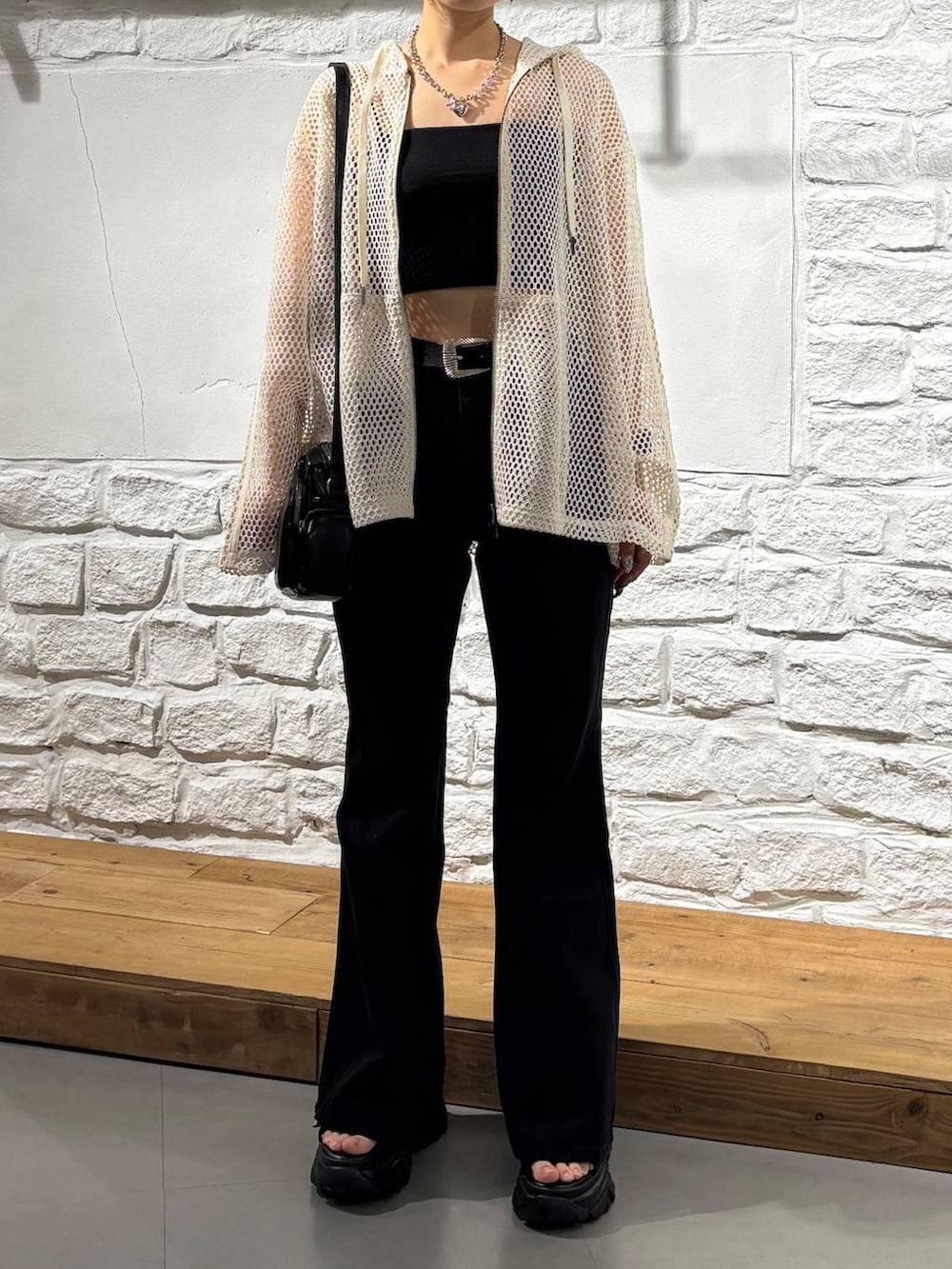 ホワイト系のパーカー、ブラック系のデニムパンツ、ブラック系のショルダーバッグを着用したレディースの夏コーディネートの3枚目の写真