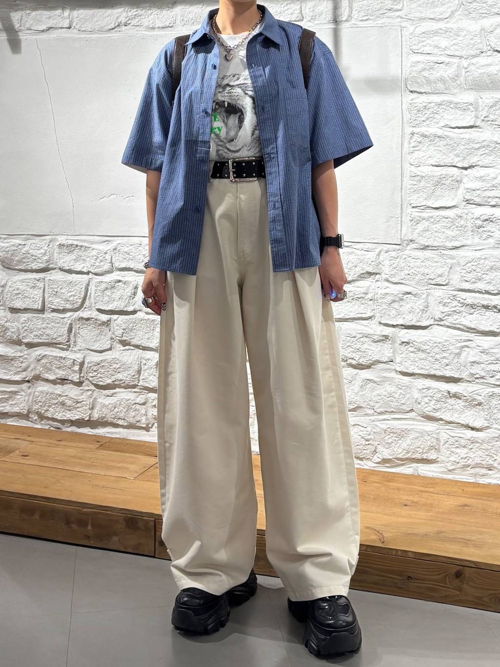 ブルー系のシャツ/ブラウス、ベージュ系のスラックス、ブラック系のスニーカーを着用したレディースの夏コーディネートの2枚目の写真