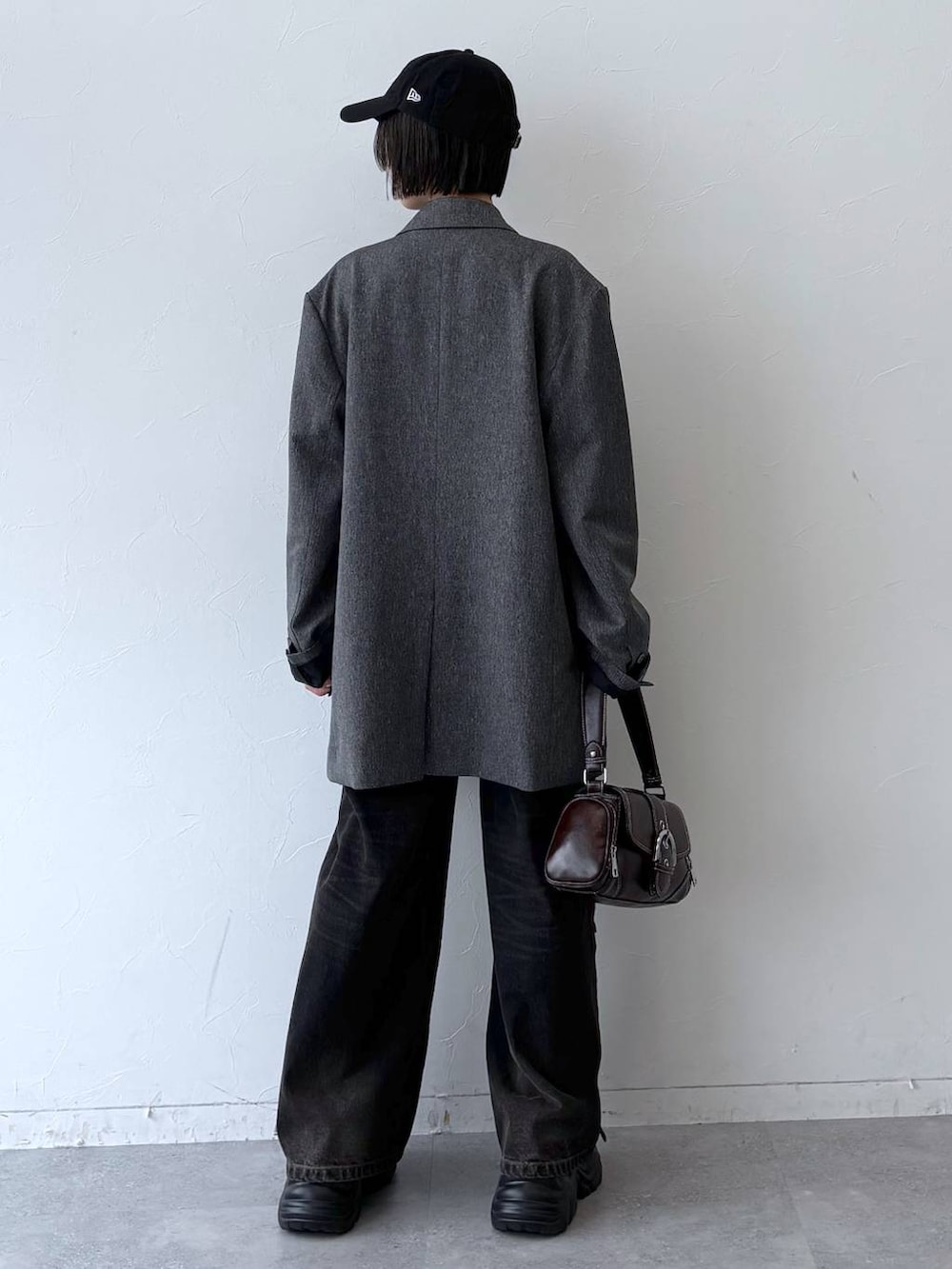 ブラック系のスニーカー、ブラック系のデニムパンツ、グレー系のテーラードジャケットを着用したレディースの秋コーディネートの6枚目の写真