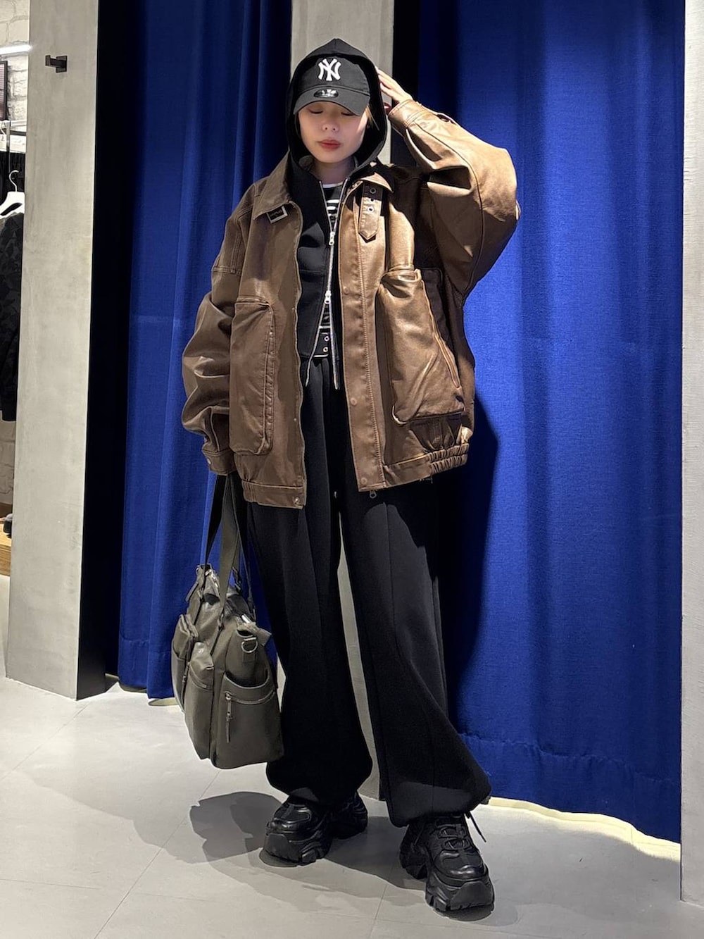 ブラック系のスニーカー、グリーン系のボストンバッグ、ブラック系のTシャツ/カットソーを着用したレディースの冬コーディネートの4枚目の写真