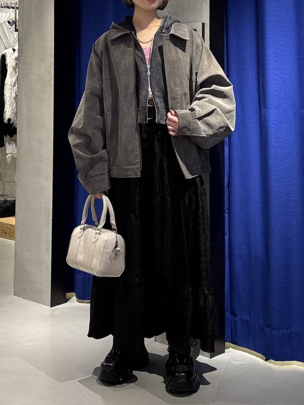 ブラック系のスニーカー、ホワイト系のボストンバッグ、グレー系のパーカーを着用したレディースの冬コーディネートの2枚目の写真