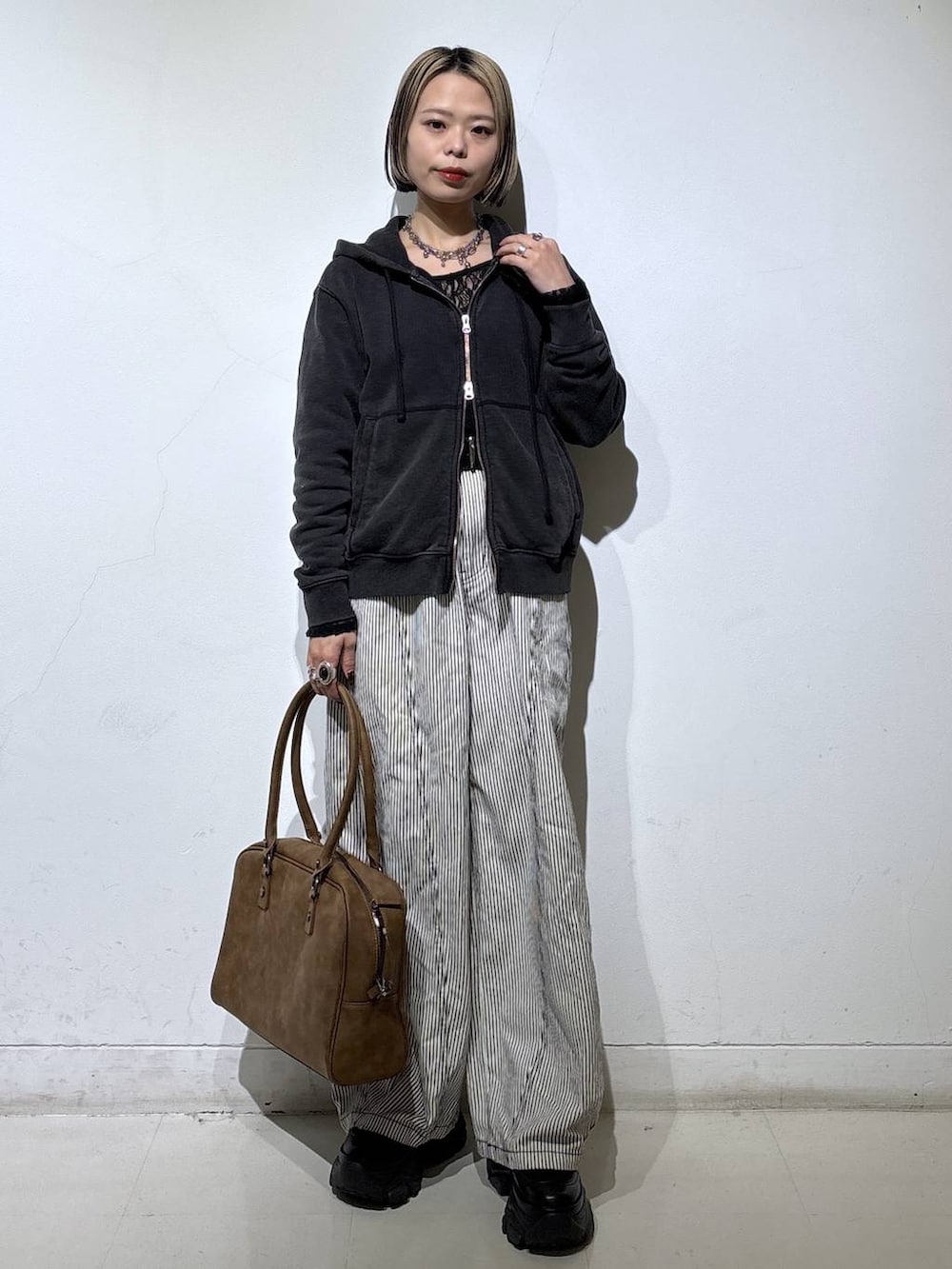 ブラック系のブーツ、ベージュ系のボストンバッグ、ブラック系のTシャツ/カットソーを着用したレディースの冬コーディネートの3枚目の写真