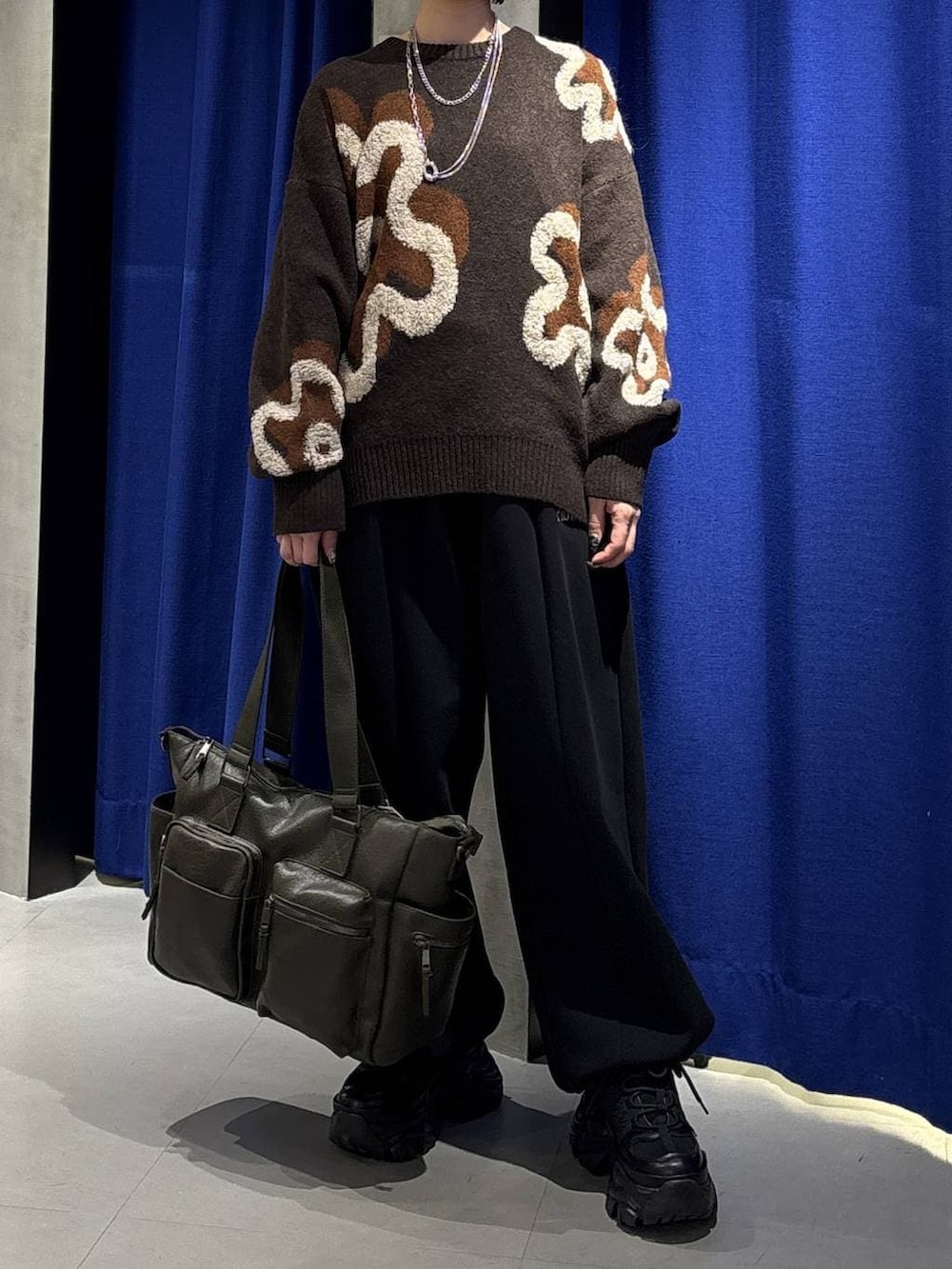 ブラック系のスニーカー、グリーン系のボストンバッグ、ブラウン系のニット/セーターを着用したレディースの冬コーディネートの2枚目の写真