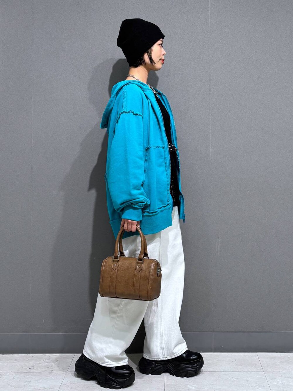 ブラック系のスニーカー、ホワイト系のスラックス、ブラウン系のボストンバッグを着用したレディースの春コーディネートの4枚目の写真