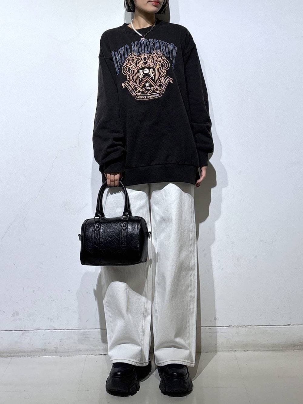 ブラック系のブーツ、ホワイト系のスラックス、ブラック系のボストンバッグを着用したレディースの冬コーディネートの2枚目の写真