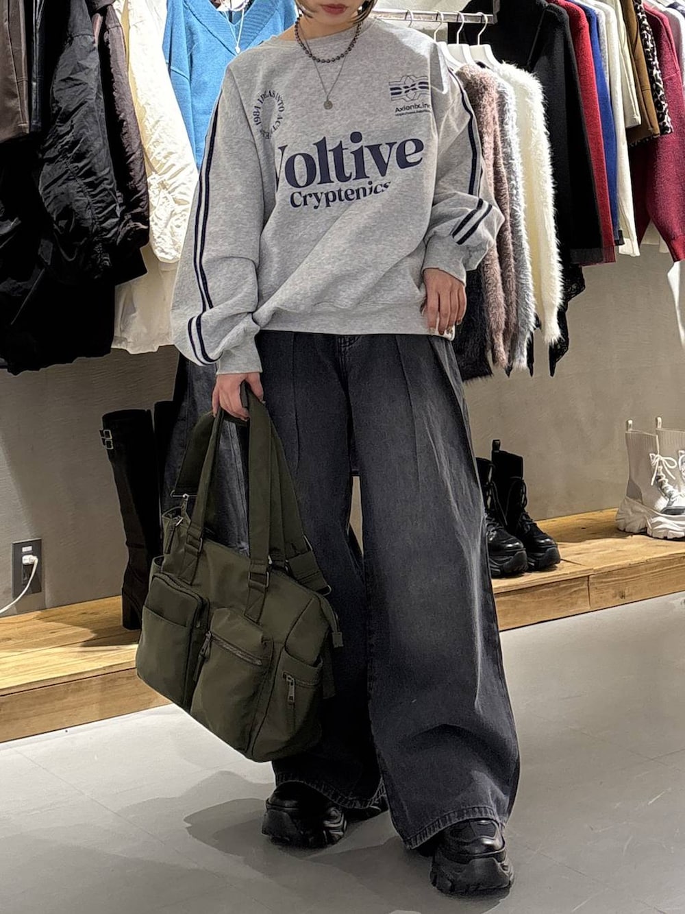 ブラック系のスニーカー、ブラック系のデニムパンツ、グリーン系のボストンバッグを着用したレディースの冬コーディネートの2枚目の写真