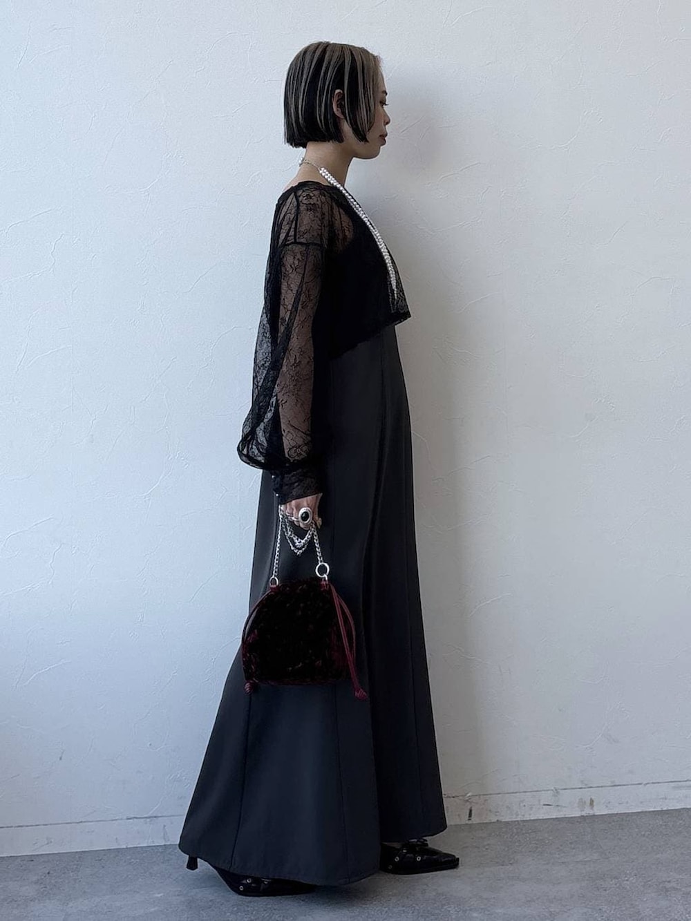 ブラック系のパンプス、レッド系のハンドバッグ、グレー系のワンピースを着用したレディースの冬コーディネートの3枚目の写真