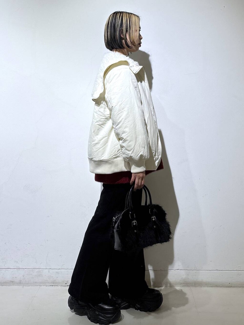 ブラック系のブーツ、ブラック系のデニムパンツ、ホワイト系のブルゾンを着用したレディースの冬コーディネートの3枚目の写真