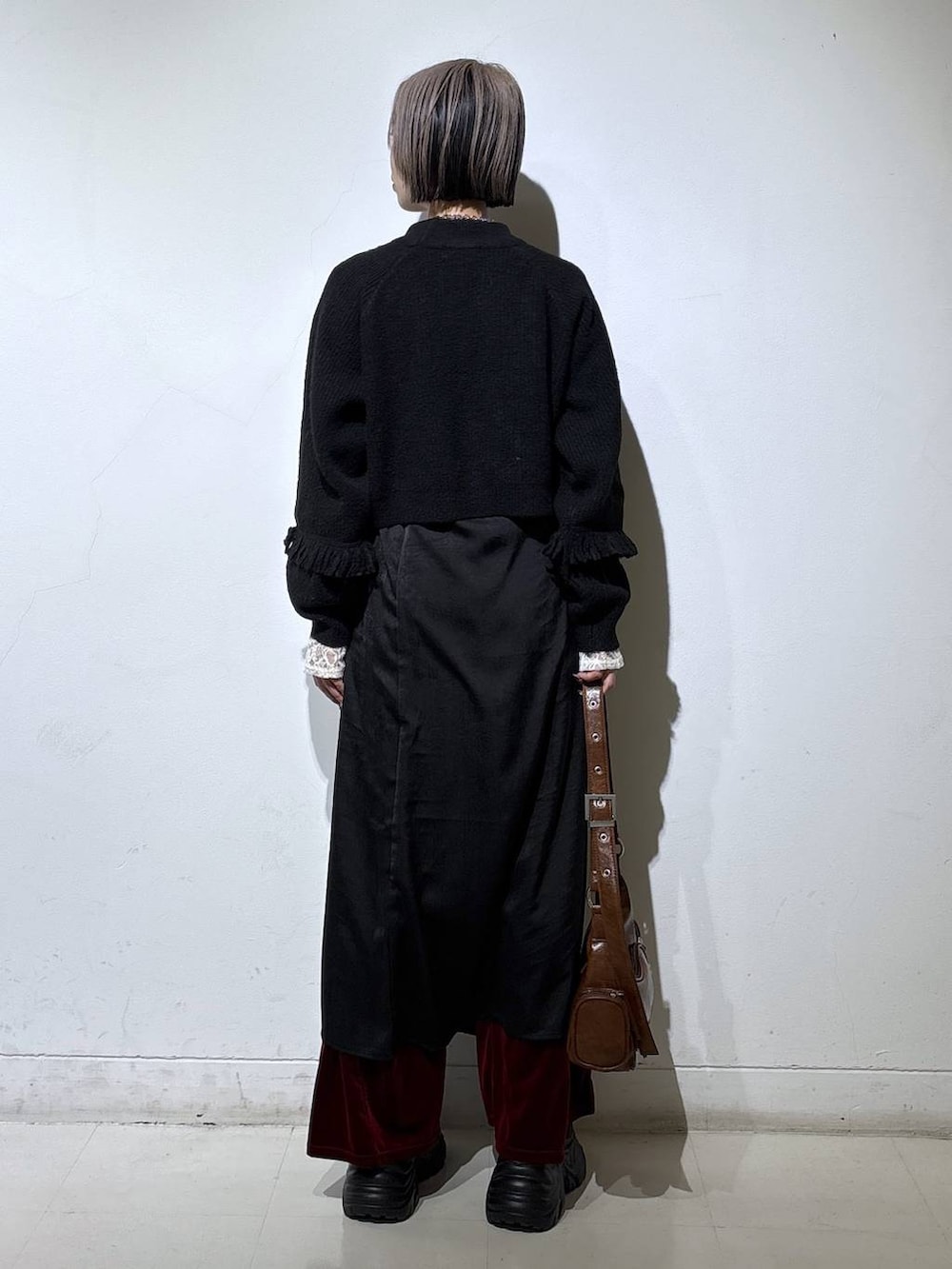 ブラック系のスニーカー、ホワイト系のTシャツ/カットソー、ブラウン系のショルダーバッグを着用したレディースの冬コーディネートの4枚目の写真