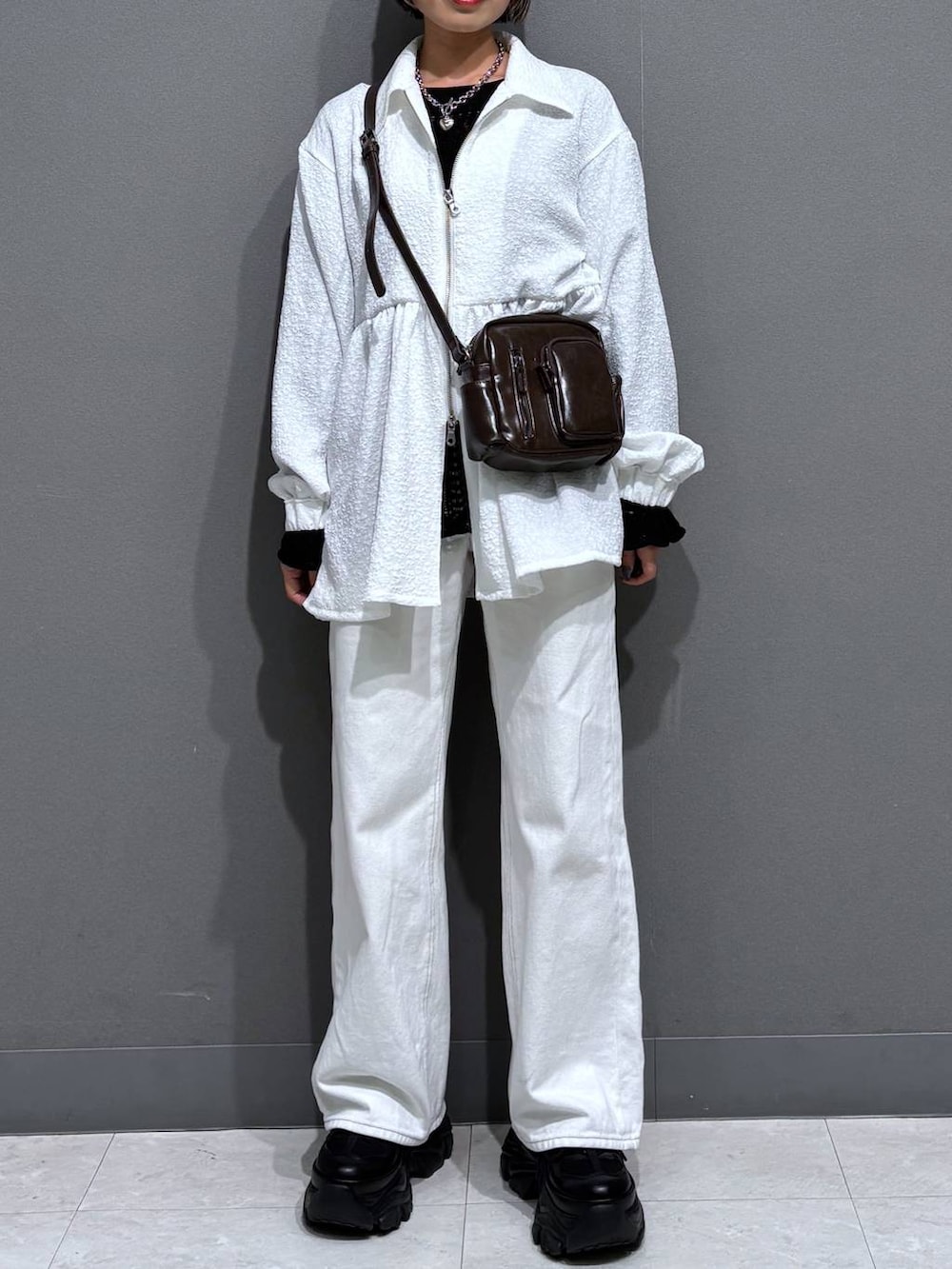 ブラック系のスニーカー、ホワイト系のスラックス、ブラウン系のショルダーバッグを着用したレディースの春コーディネートの3枚目の写真