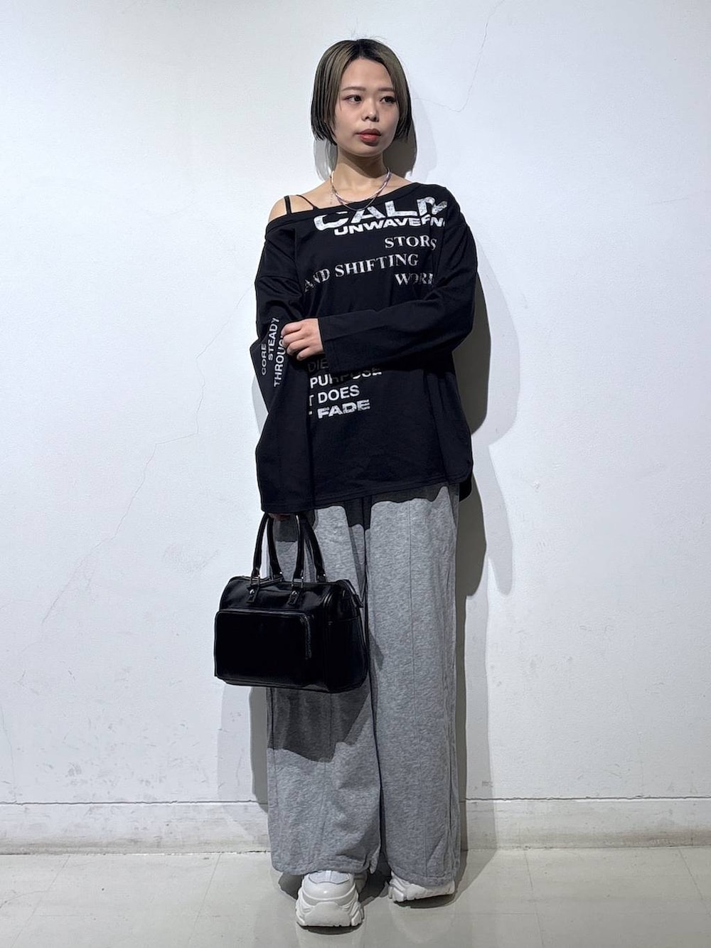 ホワイト系のスニーカー、グレー系のスウェットパンツ、ブラック系のショルダーバッグを着用したレディースの春コーディネートの2枚目の写真