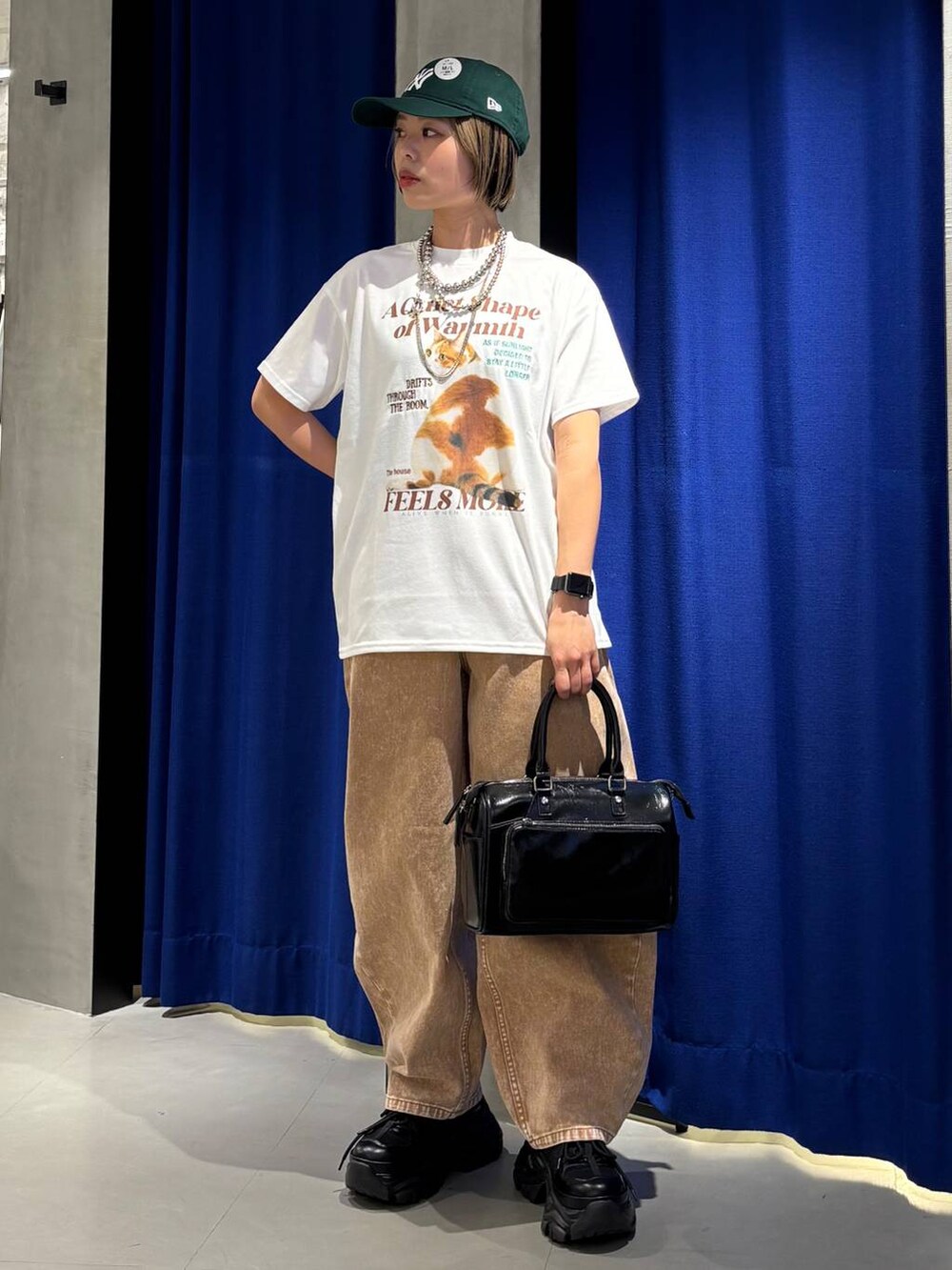 ブラック系のスニーカー、ブラウン系のデニムパンツ、ブラック系のショルダーバッグを着用したレディースの春コーディネートの3枚目の写真