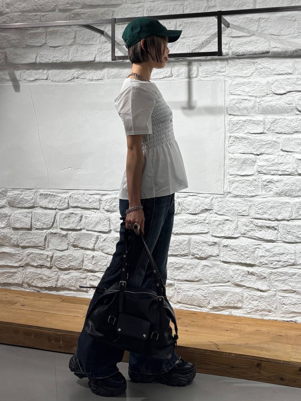 ブラック系のスニーカー、ブルー系のデニムパンツ、ブラック系のボストンバッグを着用したレディースの春コーディネートの4枚目の写真