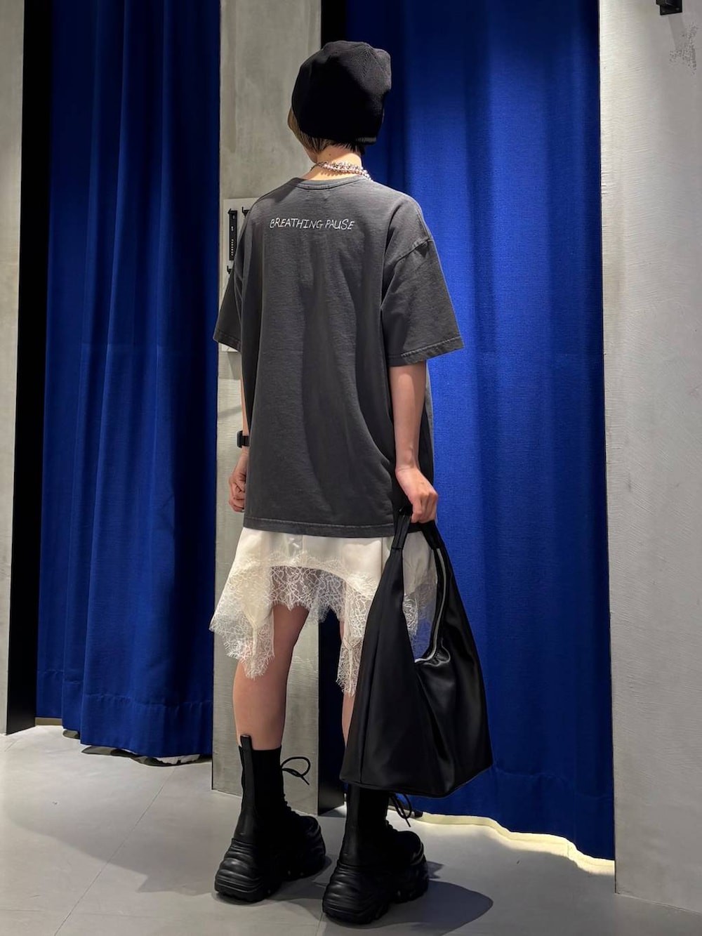 ブラック系のブーツ、ブラック系のトートバッグ、ホワイト系のチュニックを着用したレディースの春コーディネートの6枚目の写真