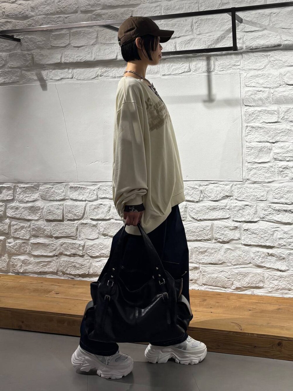 ブルー系のデニムパンツ、ホワイト系のスニーカー、ブラック系のトートバッグを着用したレディースの秋コーディネートの5枚目の写真
