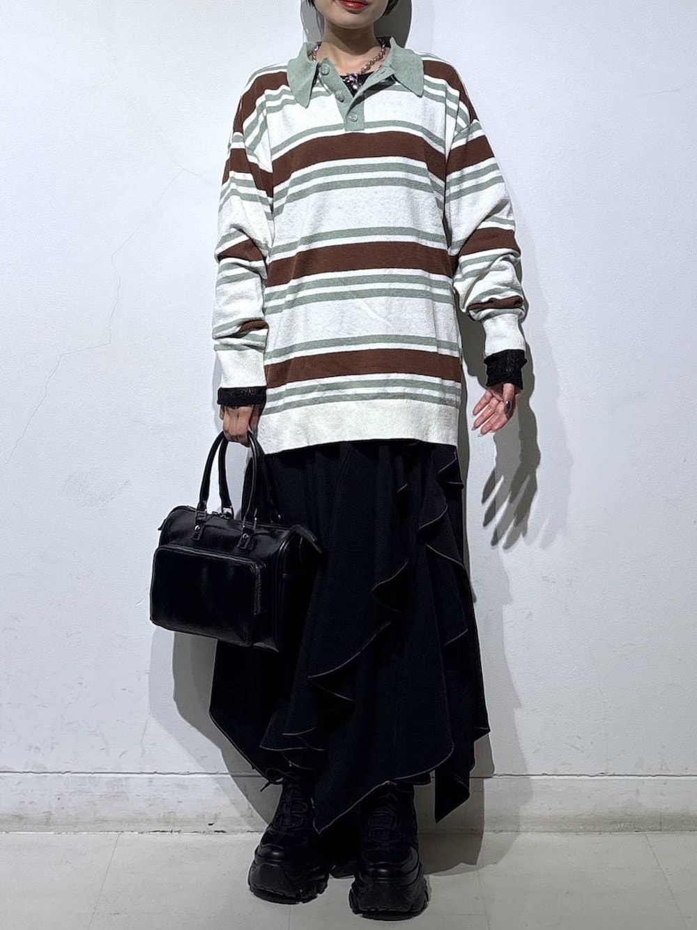 ブラック系のスニーカー、ブラック系のスカート、ブラック系のショルダーバッグを着用したレディースの春コーディネートの2枚目の写真