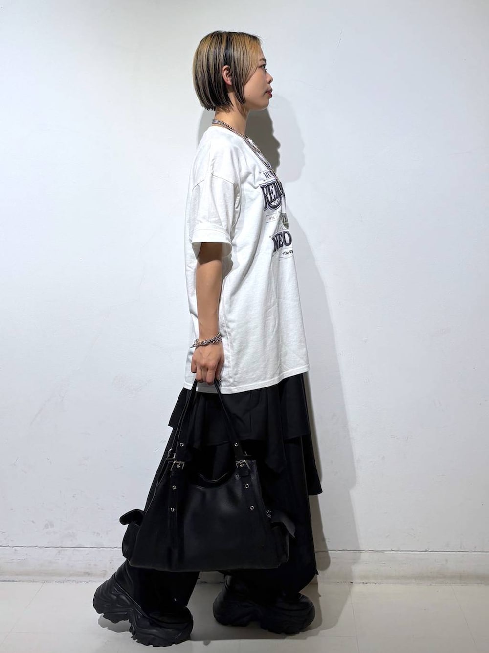 ブラック系のブーツ、ホワイト系のTシャツ/カットソー、ブラック系のハンドバッグを着用したレディースの夏コーディネートの4枚目の写真