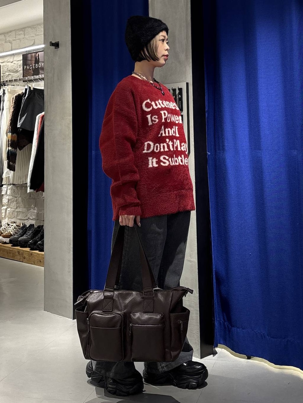 ブラック系のブーツ、ブラウン系のボストンバッグ、レッド系のニット/セーターを着用したレディースの冬コーディネートの3枚目の写真